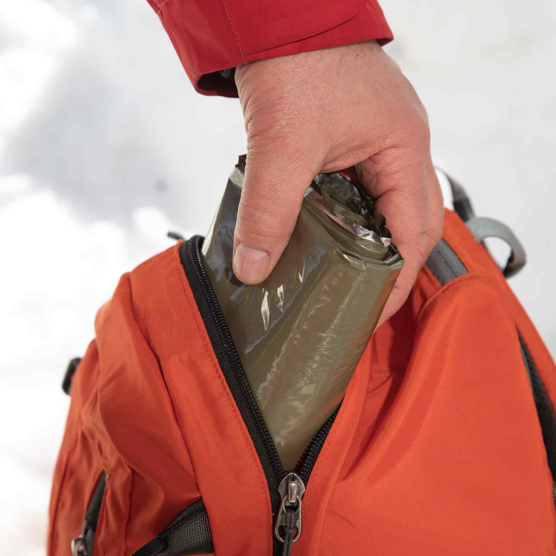 Heavy Duty Emergency Blanket being placed in a backpack